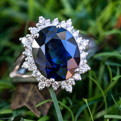טבעת דגם פרח מעוצבת עם אבן חן מרכזית ספיר כחולה בשיבוץ יהלומים בגדלים שונים מסביב